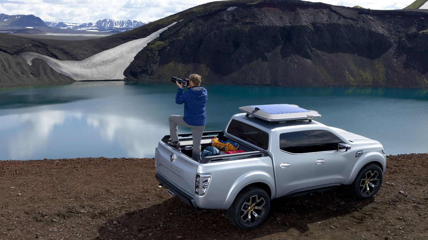 A man clicking picture of the mountains while standing on his Renault ALASKAN concept ca
